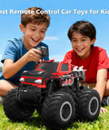 Two kids playing with Amphibious RC Monster Truck 1 16 Scale All-Terrain Off-Road Beast on grass.