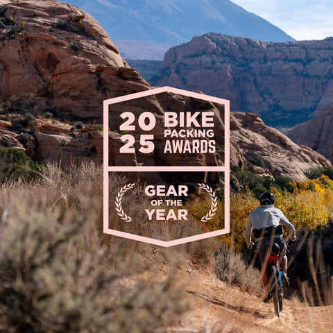 Cyclist riding on rocky trail with desert mountains, showcasing Ultra Lite Outdoor Bathroom Kit for Hiking, Trail Running, Mountain Biking, and Bikepacking.