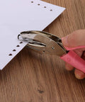 Using the Three Piece Handheld Paper Hole Punch Set With Soft Grip Handles, 5mm, 5.5mm And 6mm Holes, Pink Silver Tone on paper.