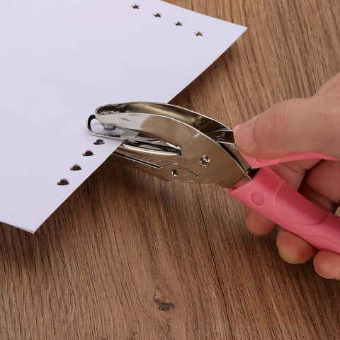 Using the Three Piece Handheld Paper Hole Punch Set With Soft Grip Handles, 5mm, 5.5mm And 6mm Holes, Pink Silver Tone on paper.