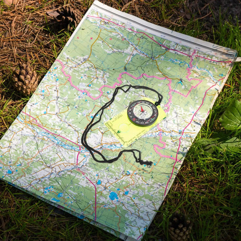 Orienteering Compass With Scale Acrylic Navigation Tool Portable Hiking Compass on top of a detailed map in nature setting