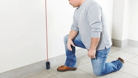 Person using Super Handy 165 Foot Blaze Laser Distance Measure with Backlit Color Display in indoor setting, showing accuracy in any lighting condition.