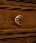 Drawer with a Set Of Six Gold Finish Cast Iron Crescent Moon Face Drawer Pulls For Celestial Decor installed on dark wood surface