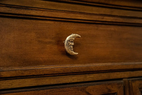 Drawer with a Set Of Six Gold Finish Cast Iron Crescent Moon Face Drawer Pulls For Celestial Decor installed on dark wood surface