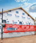 Installed Titan pump jack safety net, 22 ft long, red mesh barrier on exterior of under-construction house.