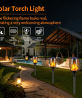 Six Pack Solar Torch Lights With Realistic Flickering Flame installed along a garden pathway at night, illuminating a patio.