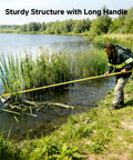 Extendable Pond Weed Cutter Kit With A Three-Sided Blade And Aluminum Poles For Cattails And Garden Weeds Angled Cutting Without Repositioning Durable Yellow Tool For Quick Yard Cleanup And Lawn Pond Maintenance. Man uses long yellow pond weed cutter at lake edge