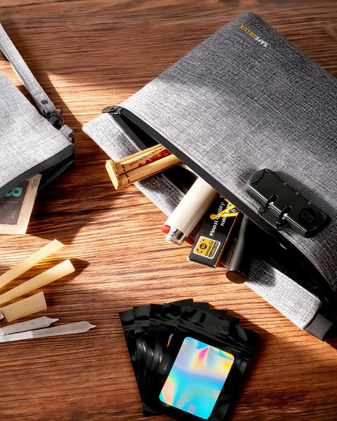 Grey smell proof bag with combination lock, odor proof container with carbon lining shown open on wooden surface, scattered items
