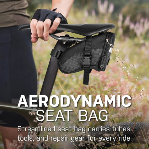 A cyclist attaching Aero Wedge Pack Small Strap Mount Seat Bag For Tubes And Tools Built For Cyclists With Reflective Trim to bike.