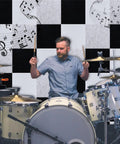 Drummer playing in front of Heavy Hitter Acoustic Wall Panels 12 By 12 Inches White Sound Absorbing Tiles, enhancing soundproofing.