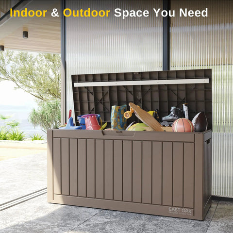 60 Gallon Deck Box Outdoor Storage Waterproof Resin Bin with open lid, holding sports equipment, on a patio
