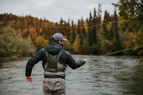 Angler using Stormshadow Fly Fishing Chest Pack With Waterproof Pocket on river, showing net slot and attachment points.