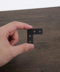 Hand holding Beefed Up Heavy Duty Stainless Steel Corner Braces 20 Pack Thickened Right Angle Brackets on wooden surface