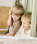 Two kids reading a book while sitting in the Ultimate Chill Cotton Sensory Cocoon Swing For Kids Autism And Adhd Therapy Support.