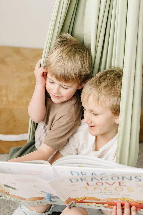 Two kids reading a book while sitting in the Ultimate Chill Cotton Sensory Cocoon Swing For Kids Autism And Adhd Therapy Support.