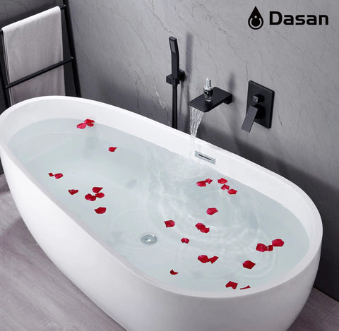 Water running from a wall mounted matte black tub faucet with hand shower into a freestanding tub with rose petals, modern look.