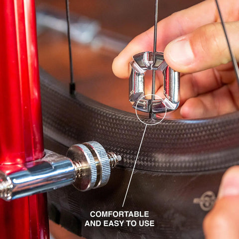 Hand using 4 In 1 Bicycle Spoke Wrench Kit With 3 Spoke Nipples Tools Plus Valve Core Remover And Valve Extender Holder on bike wheel.