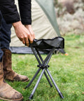 Apex Fold-Up Stool G-140 Black Grey Ultra Portable Camp Seat being set up beside a tent outdoors.