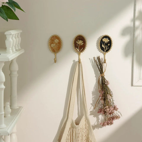 Super Clean Set Of Three Straight Up Vintage Wall Hooks With French Garden Floral Details And Classic Scalloped Metallic Hardware For Entryway Organizing And Cozy Bedroom Vibes, displaying hooks with flowers and holding bags.