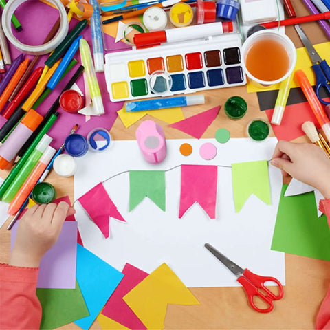 Child crafting with paper, paint, and 5 Piece Craft Hole Punch Set For Scrapbooking And Card Making, pink circle shapes visible.
