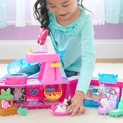 Child playing with Minnie Mouse Bowdazzling Yacht Lights And Sounds Playset With 16 Piece Figures And Accessories Pink Boat