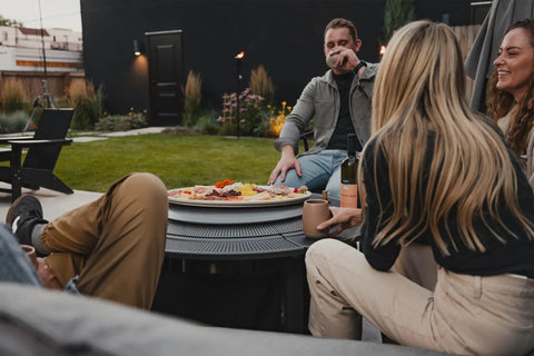 Group enjoying snacks on Surround Surface For Yukon Fire Pit Lid Durable Cold Rolled Steel Shield 34.5 Inch Diameter outdoors