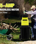 Man using Electric Wood Chipper Shredder With Fifteen Amp Motor And One Point Eight Inch Cutting Diameter Portable Wheels 50 Liter Collection Bin Mulcher for yard debris cleanup.
