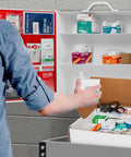 Person accessing ANSI 2021 Class B First Aid Kit Refill Pack With 160 Pieces in workplace, showing bandages and supplies.