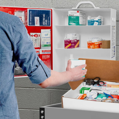Person accessing ANSI 2021 Class B First Aid Kit Refill Pack With 160 Pieces in workplace, showing bandages and supplies.