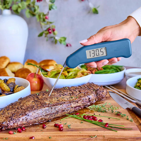 Hand using Instant Read Thermapen Inspired Digital Food Thermometer In Cayenne Red to measure beef temperature on cutting board