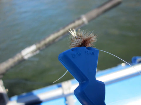 Eye Tie Fly Threader With Magnetic 3 Funnel System holding fly securely with background of water