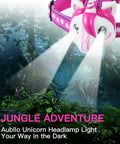 Unicorn Themed LED Headlamp For Kids And Grownups, Hands Free, with 2 Bright LEDs glowing in a jungle setting.