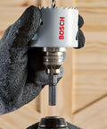 Close-up of Bosch HBT225 2-1/4 in bi-metal T-slot hole saw on arbor, held by gloved hand