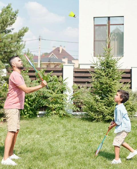 Father and son playing badminton in backyard with a 12 Pack Nylon Badminton Shuttlecocks For Backyard Fun And Outdoor Play in neon yellow.