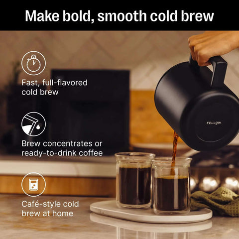 Person pouring coffee from Fellow carafe into glass mugs on a kitchen counter for cold brew preparation.