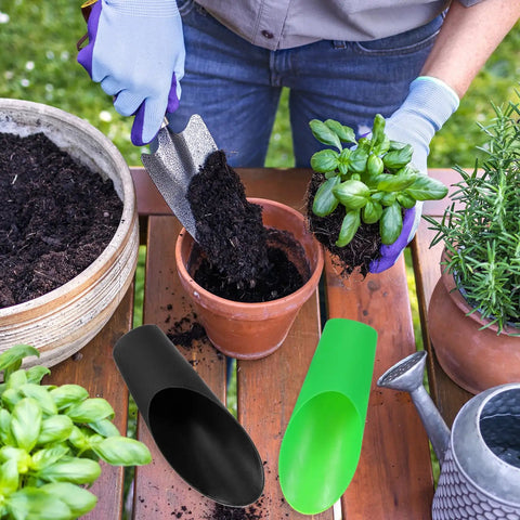 Person using silver shovel for transplanting next to Plastic Bonsai Soil Scoop 6.3 Inch By 1.8 Inch, black and green scoops shown on table.