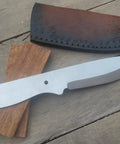 Nine Inch Stainless Outdoor Hunter Knife Kit With No Frills Blank Blade, rosewood scales and cowhide leather sheath on wood surface.