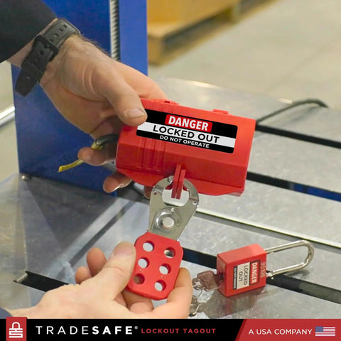 Person using industrial grade heavy duty plug lockout device for lockout tagout in red, OSHA compliant nonconductive polypropylene.