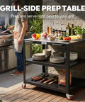 Outdoor grill with Heavy Duty Outdoor Pizza Oven Table 36 By 24 Inches With Locking Wheels 304 Stainless Steel Worktop Built Tough Three Shelf Prep Unit For Deck Patio BBQ And Parties loaded with plates and ingredients