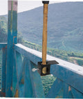 Heavy Duty Torch Clamp Holder Mount For Deck Lights And Tiki Torches On Porches Railings And Outdoor Spaces Durable Iron Clamp Mount Weatherproof Easy Install Ready To Rock For Patio Garden And Deck Party Lighting holding a torch on a blue railing overlooking a scenic view.