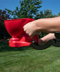 Hand using Red Ergonomic Hand Spreader with Built In Armrest and Trigger for Comfort Adjustable Reel Control in a yard