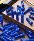 Blue 500 Pcs Plastic Drywall Anchors Ribbed Lightweight Hollow Walls Mounting Set scattered on brown wooden surface close-up view