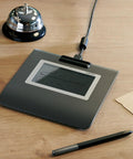Slick Low Profile Signature Pad With A Sharp 4.5 Inch Monochrome Screen Built For Hassle Free Digital Signing On Pc And Mac on a desk.