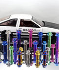 Assorted titanium bolts with flange hex heads in rainbow burnt colors displayed on a reflective surface