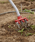 Disc Cultivator Heavy Duty Garden Tool With ComfortGEL Grip in soil, showing adjustable metal tines and long handle during weeding.