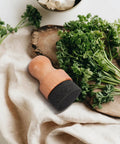 Straight Up Amazing Wooden Cutting Board Oil Brush And Built Tough Wood Wax Applicator Sponge on a kitchen towel with herbs.