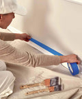 Person using painter's tape with Heavy Duty Canvas Drop Cloths 4 By 5 Feet Pack Of 2 For Painting And Floor Protection beneath.