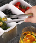 Hand using Restaurant Grade 6.5 Inch Pom Tong Set Of 6 Stainless Steel Garnish Tongs with satin finish to pick lemon slice