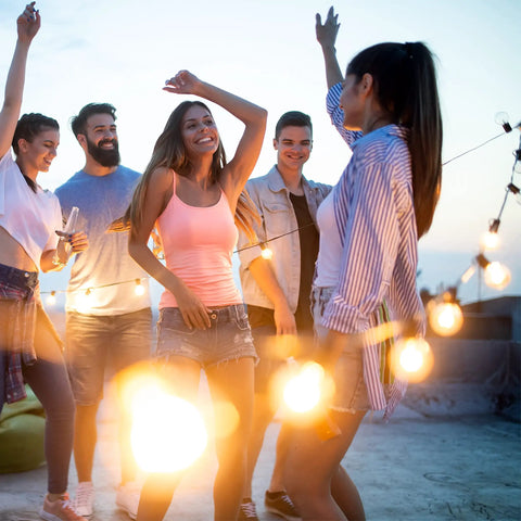 Group enjoying evening under 48Ft 15-Socket LED Outdoor String Lights With Remote Control Alexa Compatible And Smart Life App Dimmable With Timers.