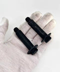 Built Tough Shoulder Bolt Set For Toro Recycler Mower, 2 black metal bolts in hand for mower deck axle hardware.